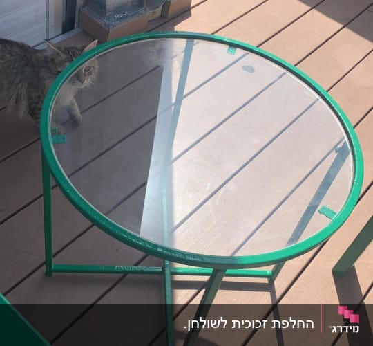 שולחן זכוכית עגול עם מסגרת ירוקה על מרפסת